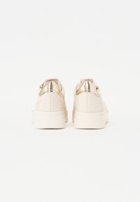 Mjuka rosa syntetiska sneakers med en glänsande guldaccent på hälen och vit gummisula, med en texturerad baksida för grepp.