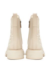 Beige nahkasaapikkaat, joissa on tikattu muotoilu, pyöristetty kärki ja kaksi vetskaria. Paksut kumipohjat täydentävät tyyliä.