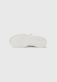 Semelle de sneaker blanche avec une adhérence en caoutchouc texturé, présentant des motifs circulaires et linéaires pour la traction. Fini lisse sans marques visibles ni accents.