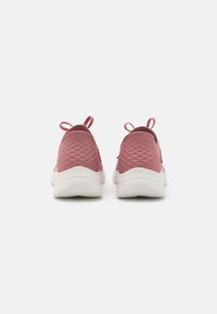 Pink athletic shoes with a textured upper, white midsole, and small pull tabs at the heel for easy wear; minimalistic design.