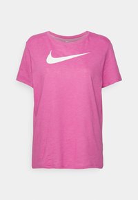 Růžové bavlněné tričko s kulatým výstřihem. Uprostřed hrudi se nachází bílé logo Nike swoosh. Krátké rukávy, volný střih.