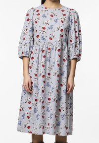 Kukallinen midi-mekko, jossa on sinisiä ja punaisia kukkia valkoisilla ja sinisillä raidoilla. Mekossa on pyöreä pääntie ja puffipuserot, joissa on rypytettyä yksityiskohtaa.