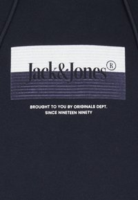 Felpa blu navy con una grafica rettangolare. Testo in bianco e grigio scuro: "Jack&Jones", con "presentata da Originals Dept." sotto.