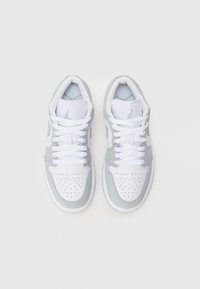 Białe i jasnoszare buty sportowe z perforowanym przodem, siateczkowym językiem i płaskimi sznurówkami. Z charakterystycznym logo na języku i boku.