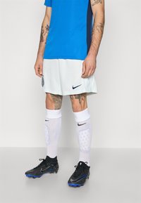 Modrý atletický dres, bílé šortky, černé fotbalové kopačky s modrými akcenty a bílé ponožky po kolena. Na tričku a šortkách je logo Nike.