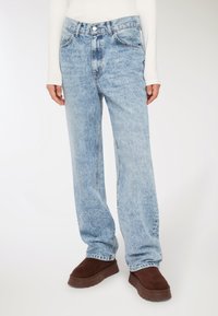 Jeans di denim azzurro chiaro con un design a gamba dritta, caratterizzati da una texture scolorita, cinque tasche e una chiusura a bottone in vita.