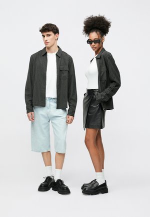 Fekete csíkos ing zsebbel, világos farmer rövidnadrág, fehér ing, fekete bőr szoknya, fekete platform cipő, világos zokni, napszemüveg.