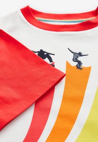 Weißes Baumwoll-T-Shirt mit roten Ärmeln, das Skateboard-Grafiken in Schwarz sowie einfarbige Farbverlaufmuster in Orange und grünen Streifen zeigt.