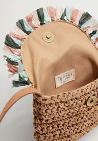 Borsa a tote in paglia intrecciata con interno beige e bordi a frange multicolori. Include un bottone a scatto in ottone e un'etichetta all'interno.