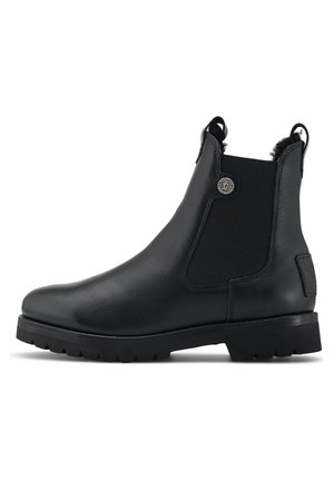 Zwarte leren Chelsea boot met elastische zijkanten, aantreklussen, nep bontvoering, ronde neus en profielzool van rubber.