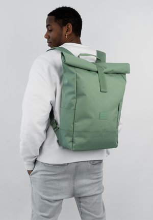 Green roll-top backpack made of durable fabric, featuring a front zip pocket, adjustable straps, and a smooth, matte texture.