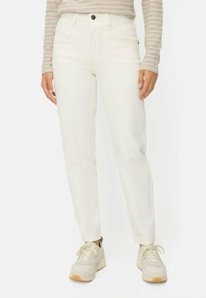 Persoon draagt off-white hooggetailleerde rechte jeans gecombineerd met beige en witte sneakers en een beige gestreept shirt met lange mouwen.