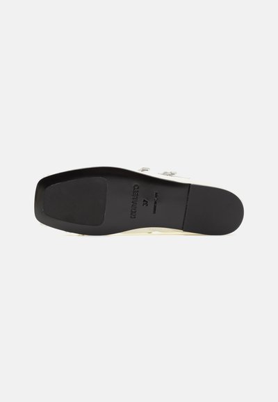 Semelle extérieure en caoutchouc noir avec surface texturée, intersemelle de couleur crème et marquage subtil embossé à l'arrière. Présente un profil élégant.