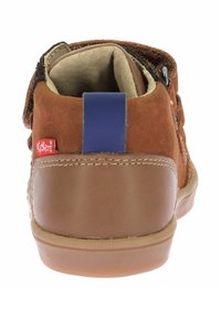 Zapato infantil de ante marrón con una suela de goma beige, acento azul en el talón y una etiqueta de marca. Diseñado con costuras reforzadas.