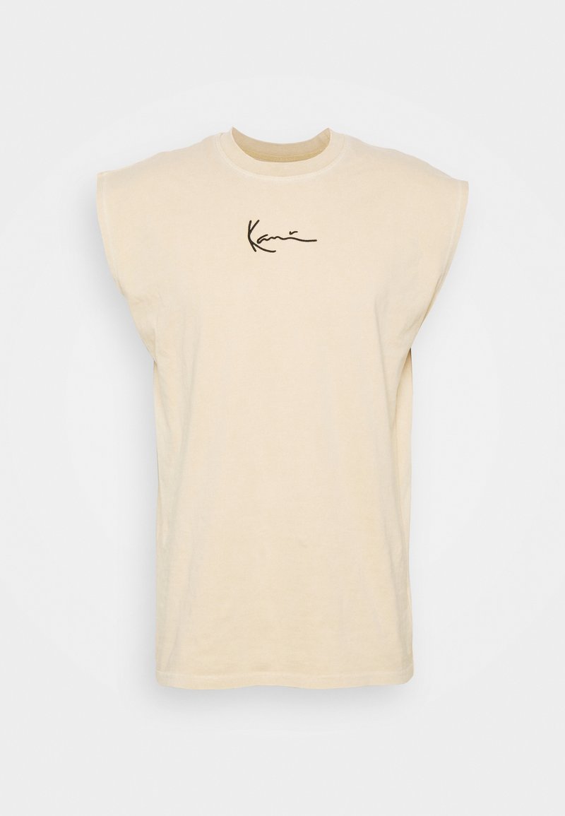 Chemise sans manches beige avec épaulettes rembourrées et logo en cursive noir centré sur la poitrine, le tout sur fond blanc.