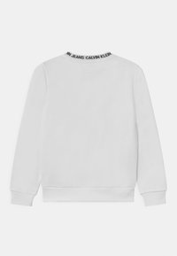 Biała bluza z długimi rękawami, okrągłym dekoltem i ściągaczami przy mankietach. Posiada kontrastowe czarne logo przy kołnierzu. Gładka tekstura materiału.