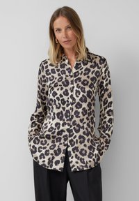 Chemise à boutons imprimée léopard en beige et noir, avec un col et des manches longues, fabriquée en tissu lisse et léger.