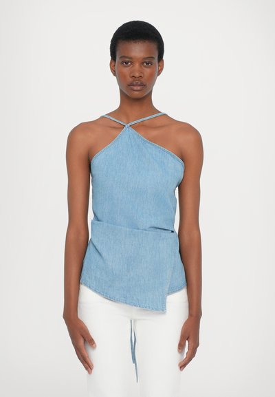 Top halter in denim con spalline incrociate, orlo asimmetrico e colore azzurro chiaro. Texture liscia con dettagli di cucitura minimi.