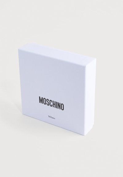 Boîte en carton blanc présentant un texte noir en gras "MOSCHINO" et "Milano" sur le devant. Texture lisse, forme rectangulaire, design minimaliste.