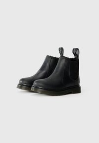 Botas de tornozelo em couro preto com painéis laterais elásticos, sola de borracha texturizada e alças de puxar com marca. Acabamento liso com dedos arredondados.