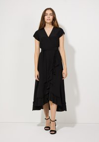 Schwarzes Wickelkleid mit kurzen Ärmeln, versehen mit einem Rüschensaum und einer Bindegurt. Das weiche Material und die fließende Silhouette verleihen dem Design eine besondere Note.