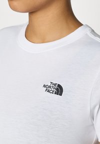 Λευκό βαμβακερό T-shirt με στρογγυλή λαιμόκοψη και μικρό μαύρο κεντητό λογότυπο "The North Face" στην αριστερή περιοχή στο στήθος.