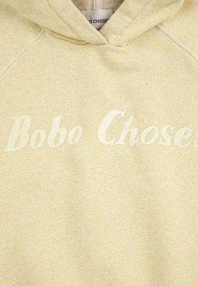 Sweat à capuche beige clair avec le texte "Bobo Choses" imprimé sur la poitrine dans une teinte légèrement plus claire.