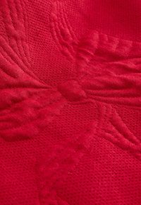 Tissu rouge présentant un motif floral en relief avec une texture détaillée, réalisé en tissu doux et respirant, avec une finition tricotée lisse.
