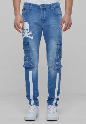 Pantalones cargo de mezclilla azul con un diseño de calavera y tibias blancas, dos bolsillos laterales, detalles de salpicaduras y rayas blancas a lo largo de las piernas.