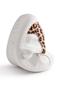 Zapatilla blanca con suela curvada, con acentos de estampado de leopardo y detalles de pedrería. Textura de cuero suave y diseño flexible.