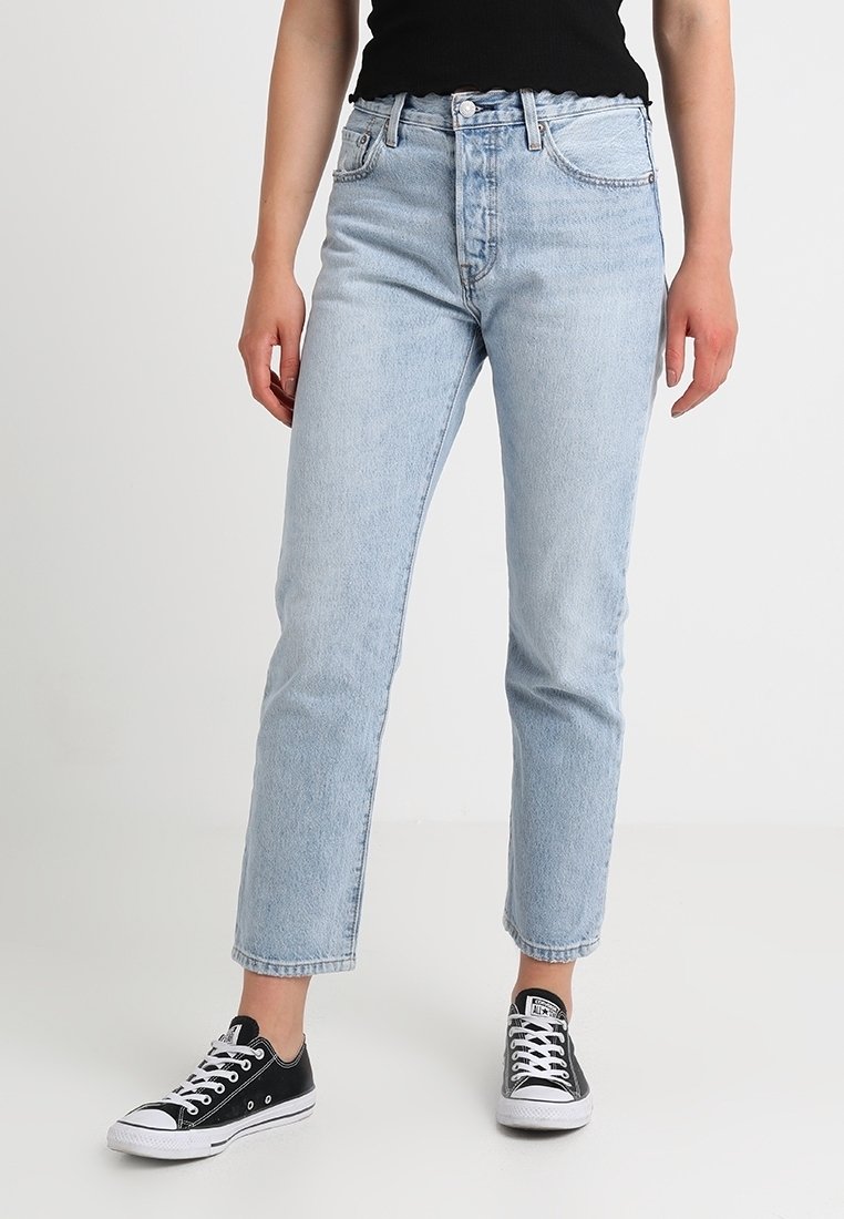 Světle modré džíny s rovný střih, vysokým pasem, pěti kapsami a předním zapínáním na knoflíky, doplněné černými teniskami Converse.