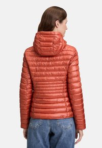 Rød polstret jakke med hætte, der har et quiltet design og blank overflade. Ryggen fremviser vandrette syninger og letvægtsstof.