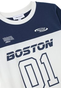 Camiseta de algodón en azul marino y blanco con estampado "BOSTON 01", cuello redondo y diseño en capas con detalles de "1988 desde" y "GIRA MUNDIAL DE INAUGURACIÓN".
