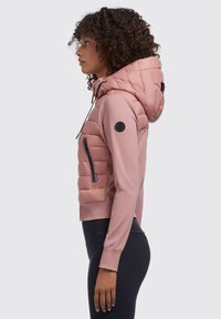 Rosa Hybridjacke mit gepolstertem Kapuze, Reißverschluss-Seitentasche und gerippten Bündchen; kombiniert glatte und gesteppten Texturen.