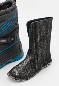 Zwarte textielboot met een glanzend, textuur oppervlak en blauwe stiksels, naast een zwarte en blauwe waterdichte boot met een gevoerde enkel.