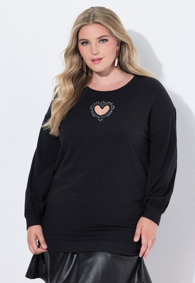 Sudadera negra con un corte de corazón en el centro, rodeado de cuentas decorativas. Mangas largas y un corte relajado con puños acanalados.