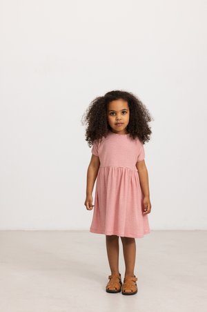 Vestido listrado em vermelho e branco com mangas curtas, decote redondo e saia rodada; combinado com sandálias de tiras castanhas.