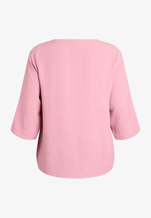 Różowy, długi rękaw z luźnym krojem i prostym, okrągłym dekoltem. Tekstura jest delikatnie wypukła, co podkreśla jej wizualne zainteresowanie.