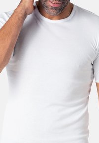 T-shirt blanc à manches courtes en tissu doux, avec un col rond classique et une silhouette ajustée. Texture lisse sans motifs.
