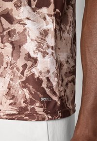 Brunmønstret treningstrøye med teksturert finish og "DRYCELL"-merke på nederkanten. Utdypende design med ulike nyanser av brunt.