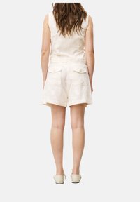 Ärmelloses Leinenoberteil und Shorts in hellem Cremeton, mit einem dezenten Blumenmuster und hinteren Taschen mit Knopfverschlüssen.