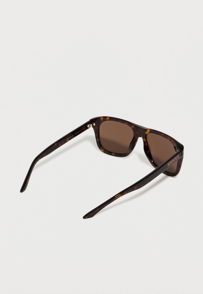 Tortoiseshell frame sunglasses with dark brown square lenses, Gucci logo on the temples, shown from a rear angled view on a white background.