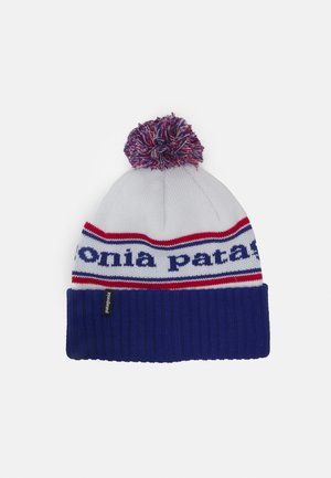Knit beanie in white, blue, and red. Features a pom-pom on top and a cuff band with "patagonia" in blue lettering. Textured ribbed design.