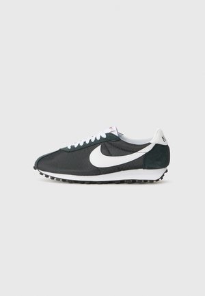 Sneakers Nike em malha preta com swoosh branco, cordões brancos e detalhes em camurça verde-escuro. Apresenta uma sola em borracha preta texturizada.