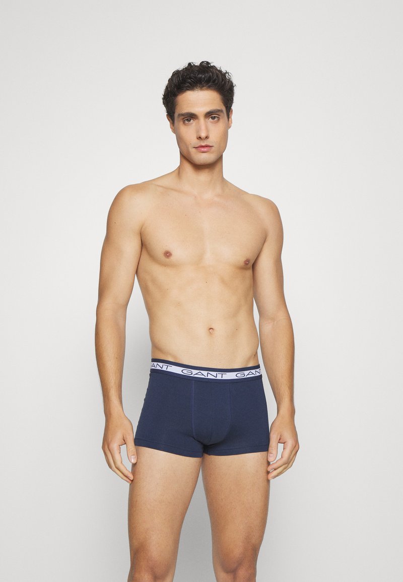 Dark blue boxer briefs with a white logo waistband, made of soft fabric. The design features a snug, fitted cut and minimal stitching details.