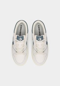 Ζεύγος λευκών και γκρι αθλητικών παπουτσιών Converse με κορδόνια, σε θέα από πάνω, σε απλό λευκό φόντο.