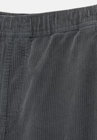 Donkergrijze corduroy stof met een geribbelde textuur, voorzien van een elastische tailleband en subtiele stikseldetails.