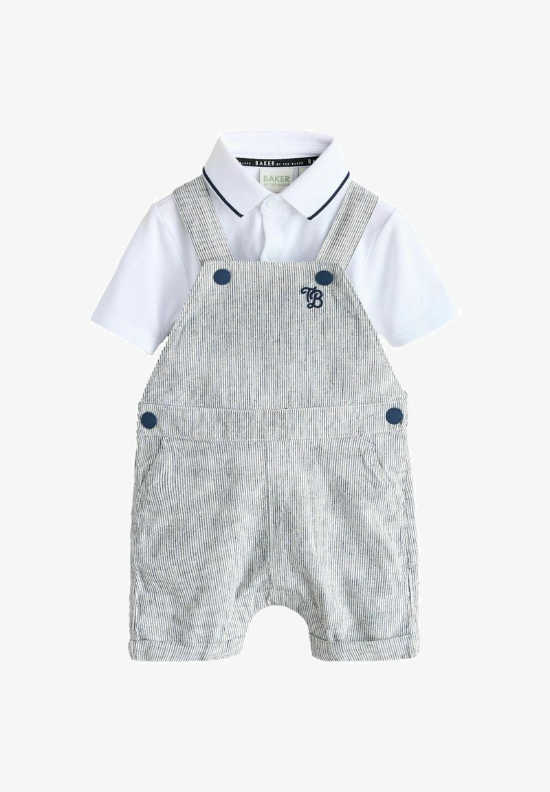 Polo blanc à manches courtes avec bordure marine, associé à une salopette courte grise à fines rayures, ornée de boutons marins et d'une broderie "TB" sur la poitrine.