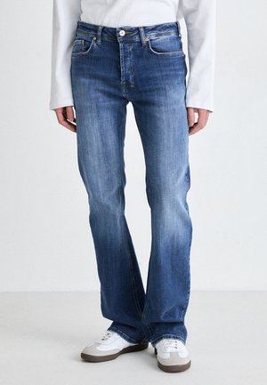 Bleka blå denimjeans med rak passform, femfickorsdesign och bältesöglor; tillsammans med vita sneakers med grå accenter.