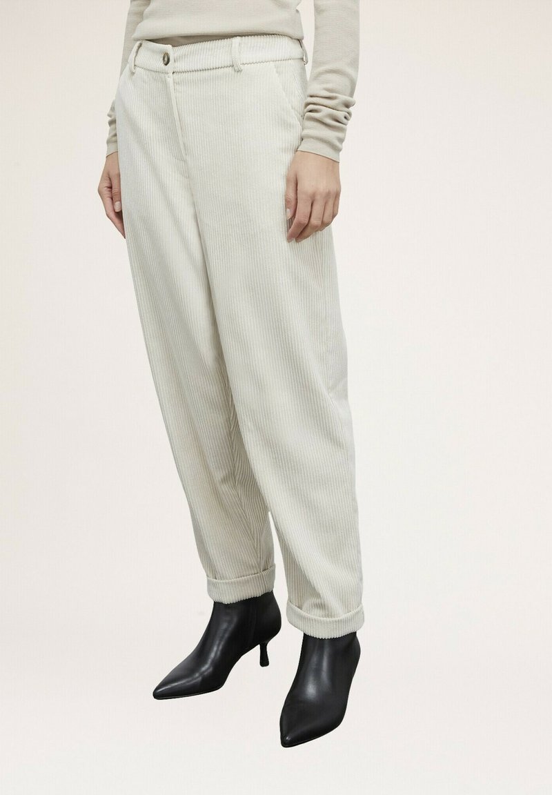 Pantalons en velours côtelé beige clair avec une coupe décontractée, dotés d'un ourlet retourné et d'une ceinture avec un bouton. Assortis avec des escarpins noirs à bout pointu.